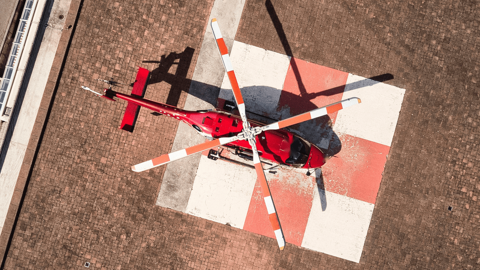 Overhead view of a red helicopter on a rooftop helipad, illustrating hospital choice among air ambulance providers.