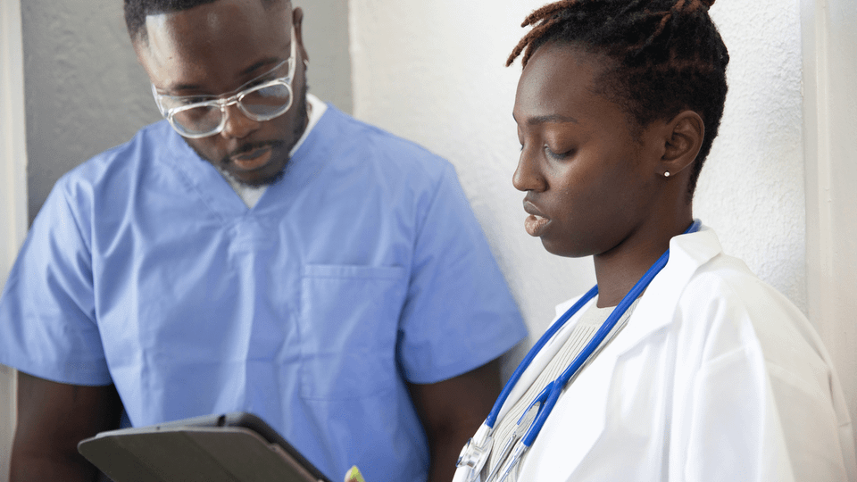 A nurse and a doctor review a tablet together, reflecting air ambulance requests placed from inside clinical workflows.