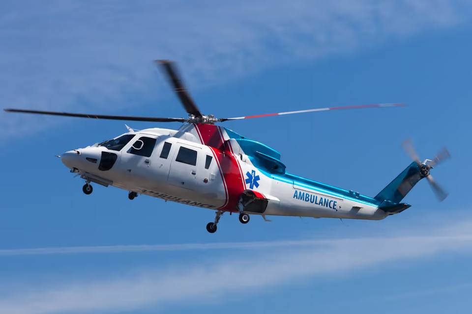 Medical helicopter landing on a hospital rooftop helipad at dusk