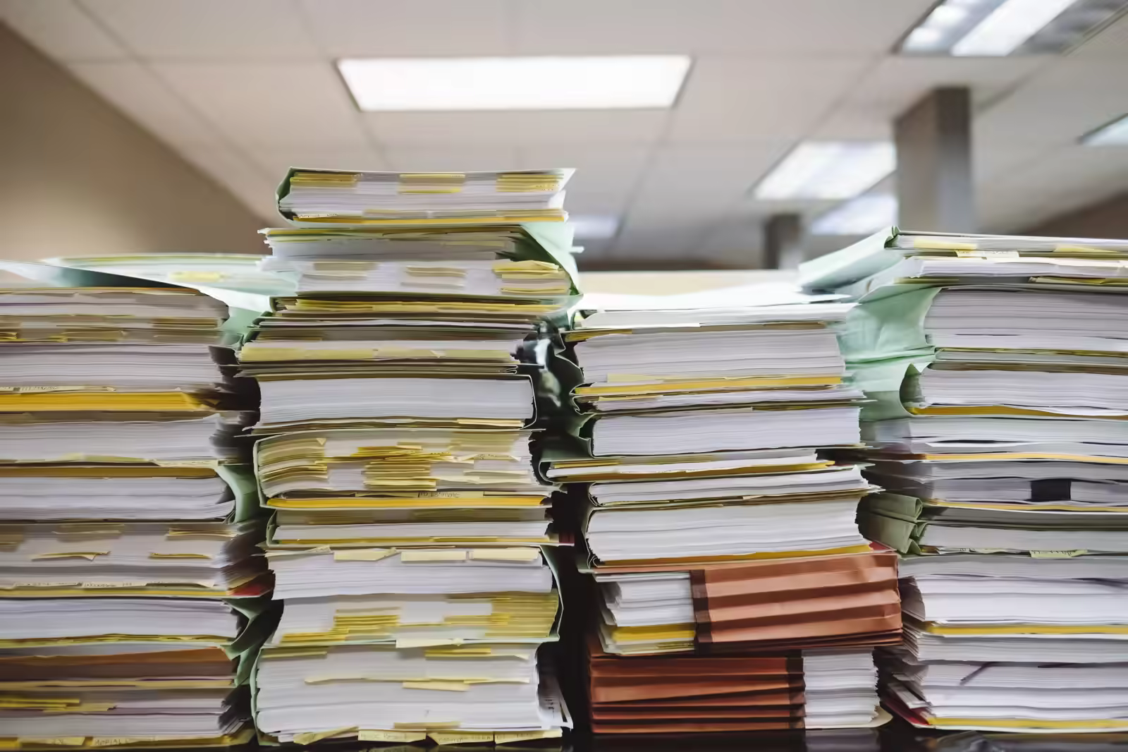 Nurse surrounded by paperwork at a nurses' station looking overwhelmed