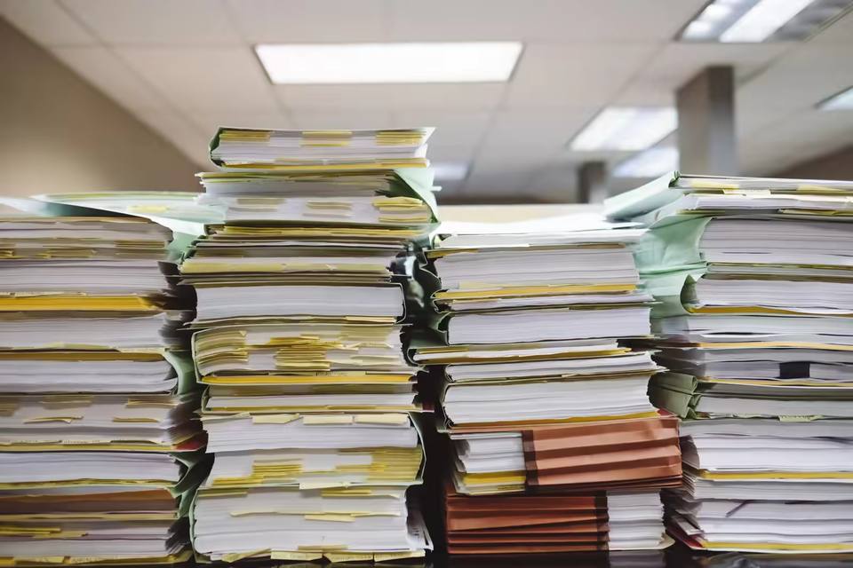 Nurse surrounded by paperwork at a nurses' station looking overwhelmed