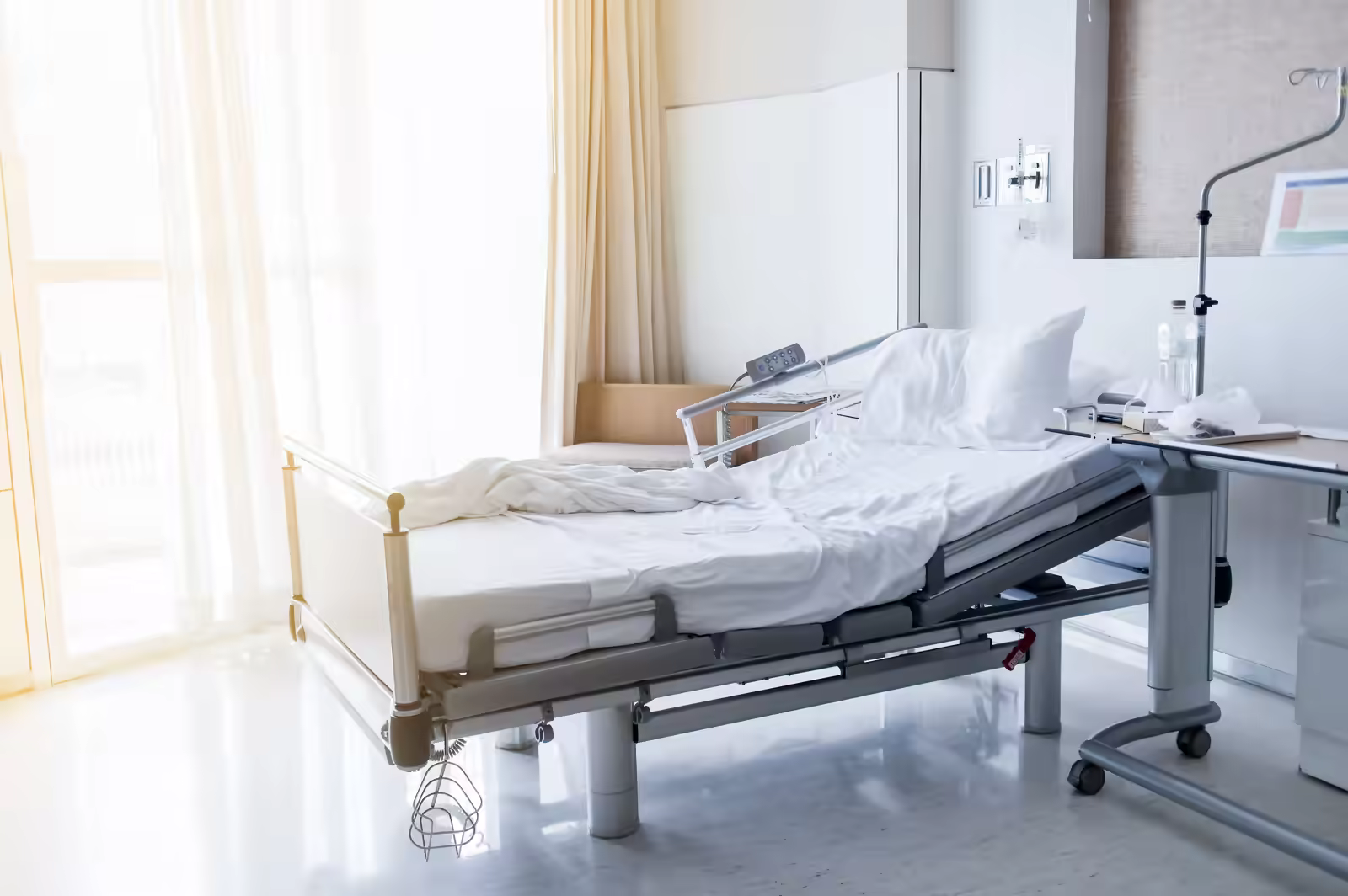 Hospital bed being prepared by nursing staff for the next patient
