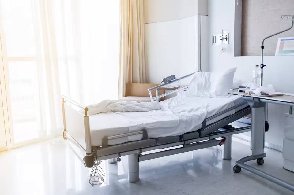 Hospital bed being prepared by nursing staff for the next patient