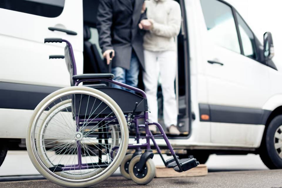 Elderly PACE participant being assisted into a medical transport vehicle