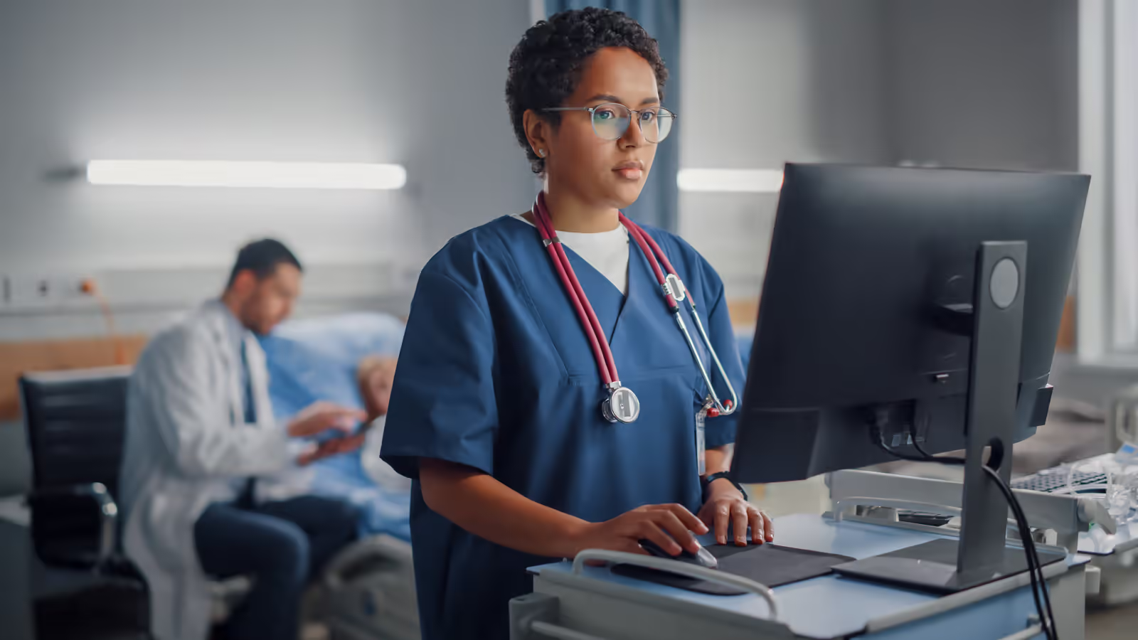 Clinician using an EHR system on a desktop monitor at a hospital workstation